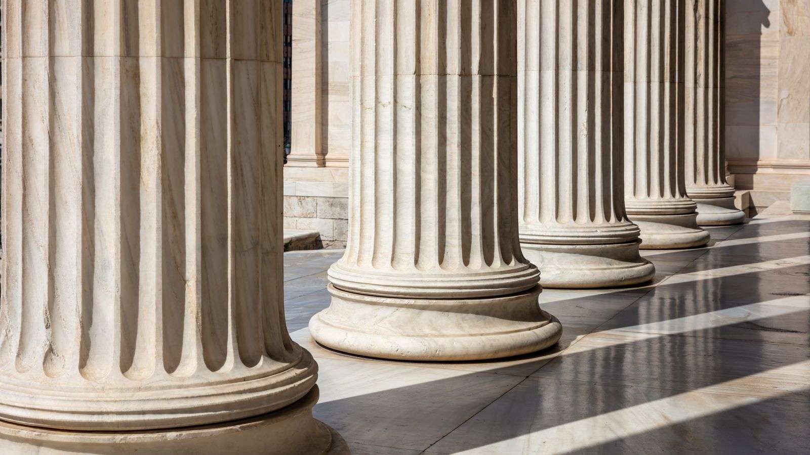 A row of fluted marble columns casting shadows across a stone floor